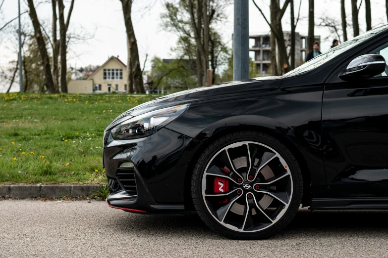 a black car with red ke pads parked next to a forest