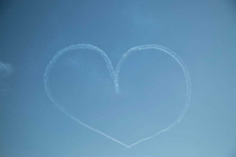 a heart made with smoke against a blue sky