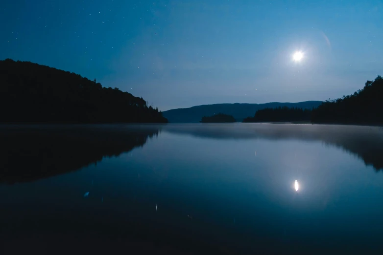 a body of water with a moon and trees in the background