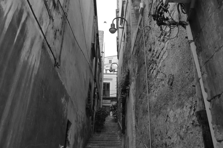 a narrow alleyway in a city with a bicycle hanging off the wall