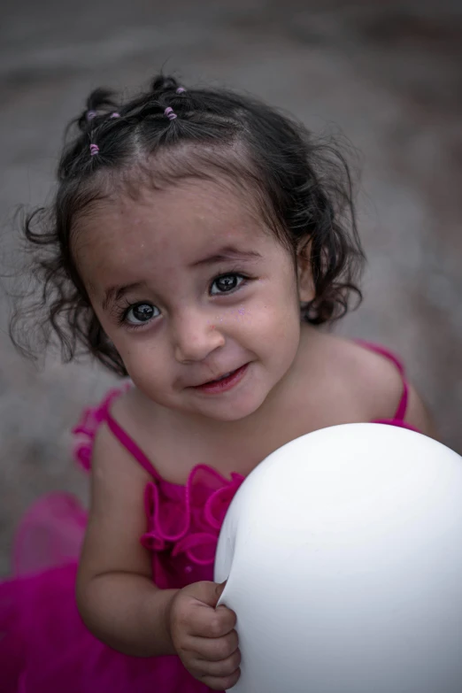 a girl in a pink dress holds a white frisbee