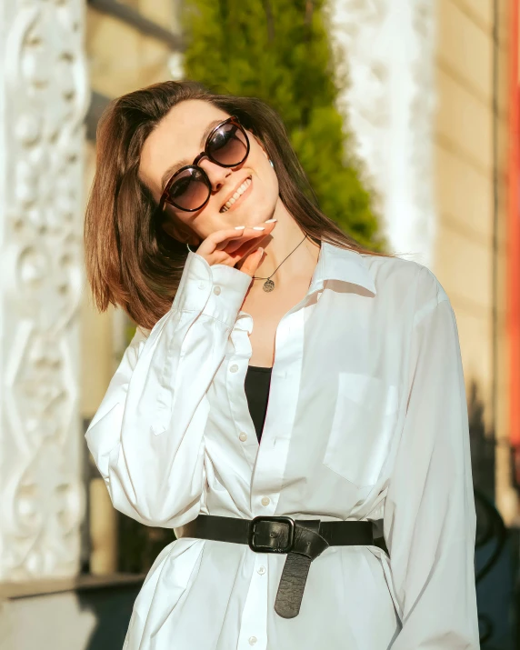 a woman is posing in front of a white building