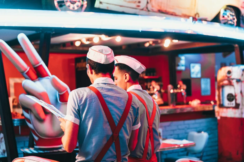 two guys are wearing uniforms and hats in a food truck