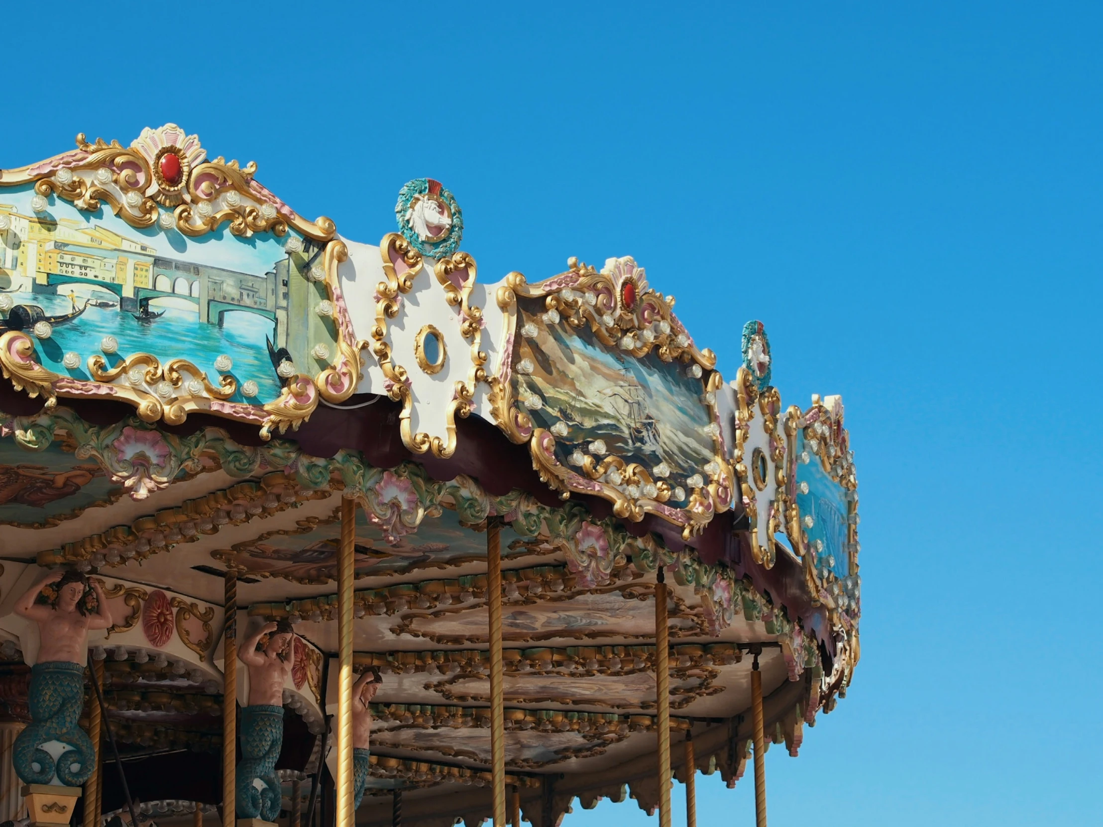 an ornate wooden carousel against a blue sky