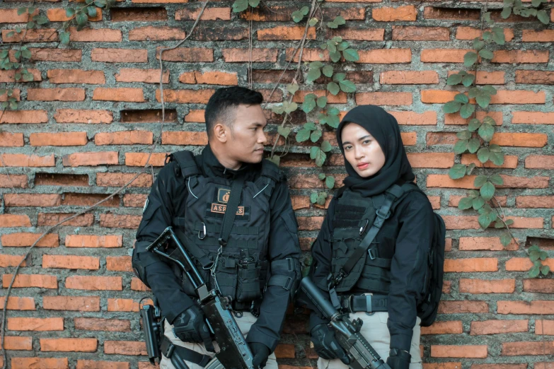 a man and woman dressed in police uniforms are standing against a brick wall