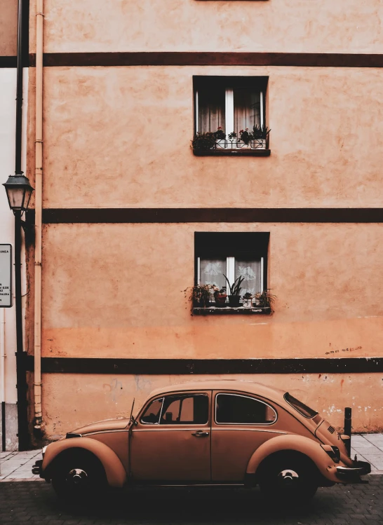 an old car parked in front of a pink building