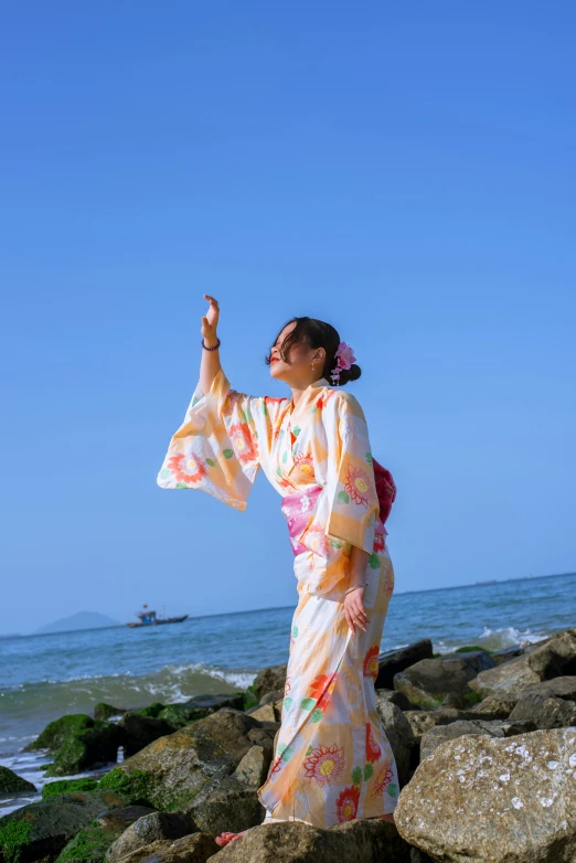 a woman dressed in an oriental style outfit stands on rocks