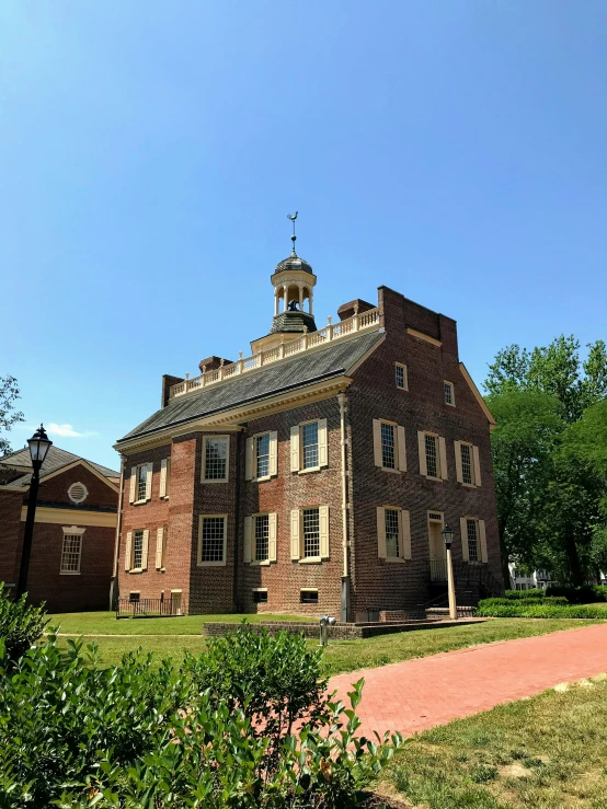 a large brick building in the woods under a bright blue sky