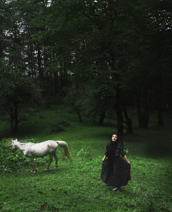 a woman standing in front of a white horse