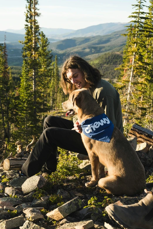 a person that is sitting down and holding a dog