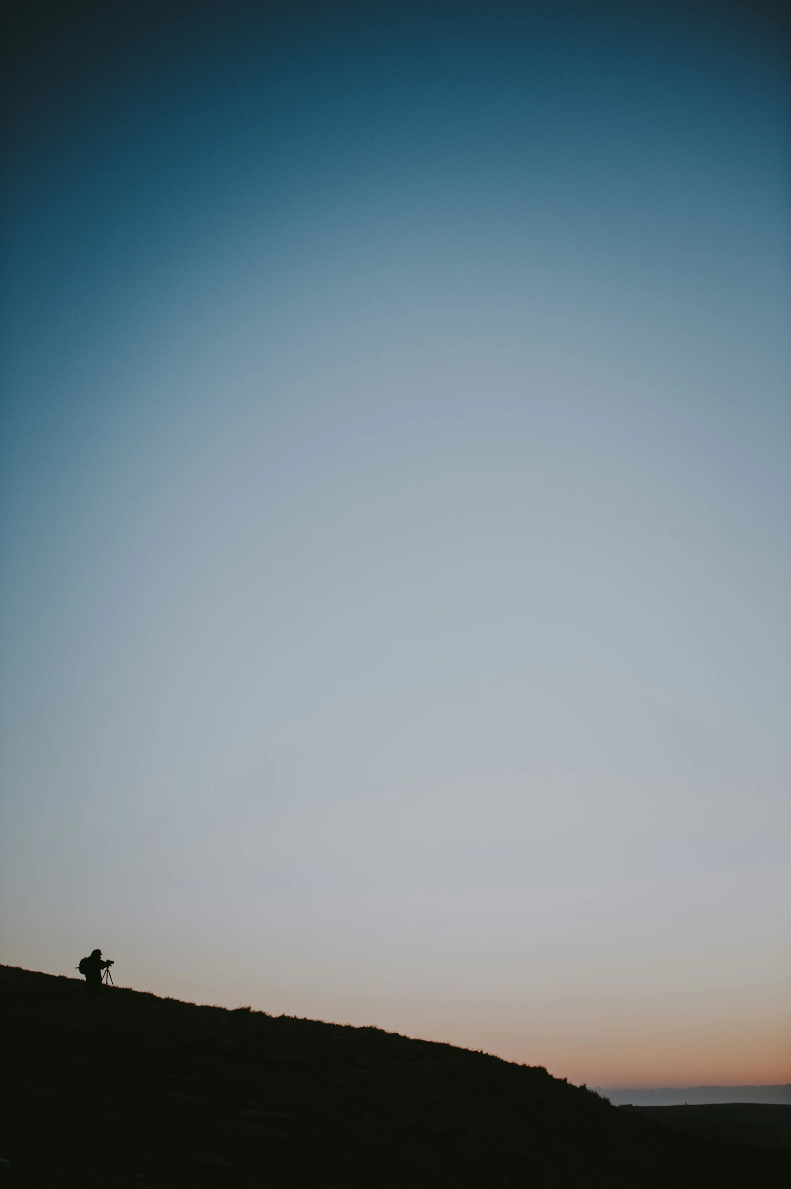 two people sitting in the shade on a hillside