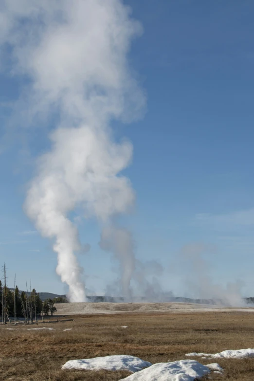 a large plume of steam rising from a desolate ground