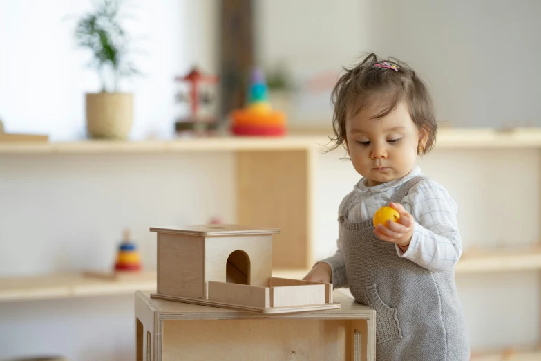 a  with her hand in her mouth plays with a house