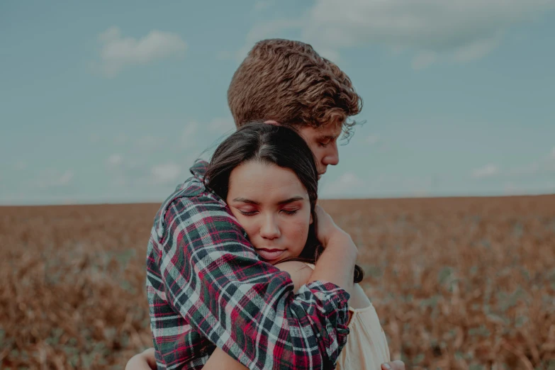 a young couple emcing in front of a large field of tall grass