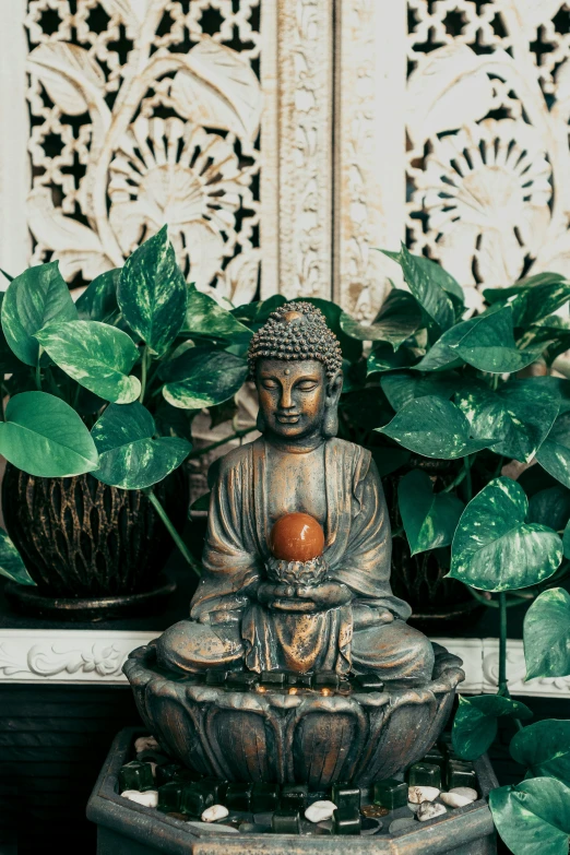 a small statue of a buddha next to some plants