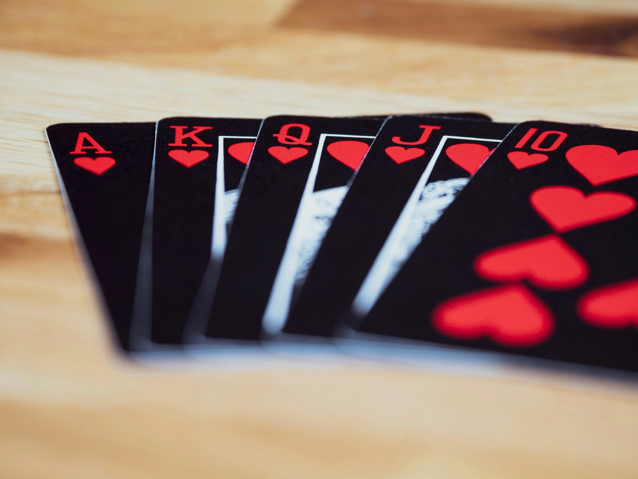 four cards have hearts on them against a wooden background