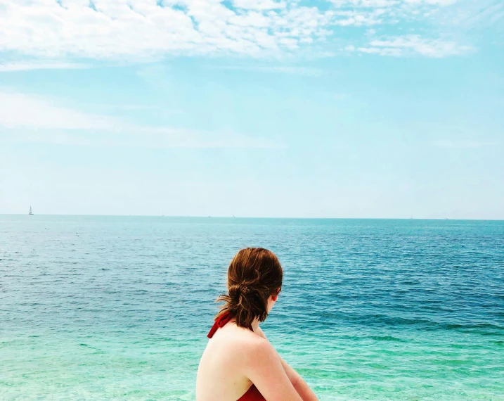 a woman is sitting on a beach and looks at the water