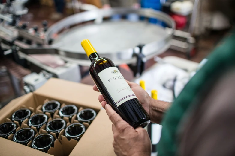 a man is holding a bottle of wine and there are some glasses near it