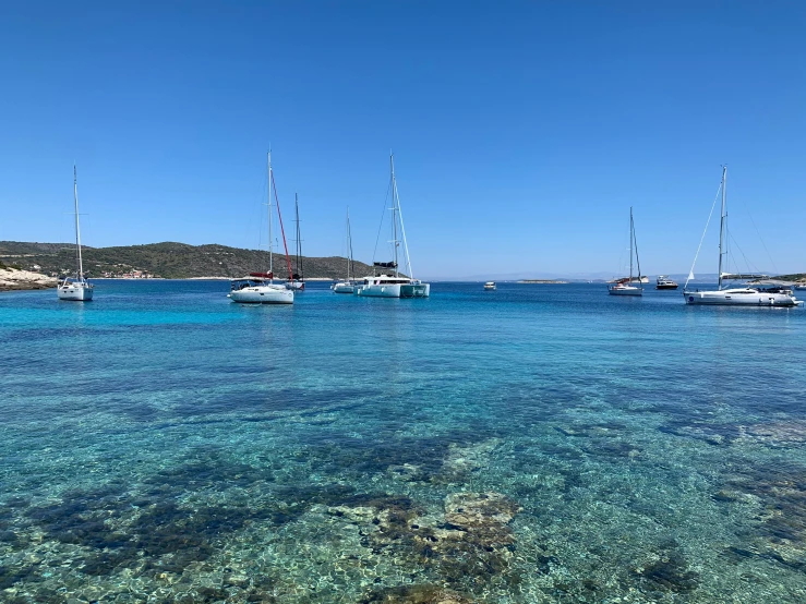 sailboats are sitting out on the water near shore