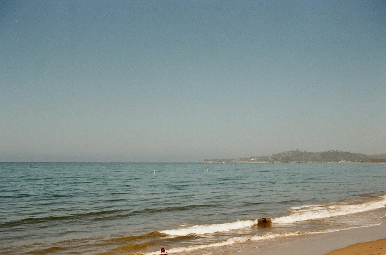 the ocean is on the beach while people are on the sand and in the water