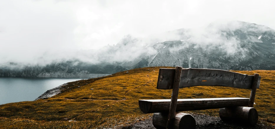 a bench is on the grass overlooking the water