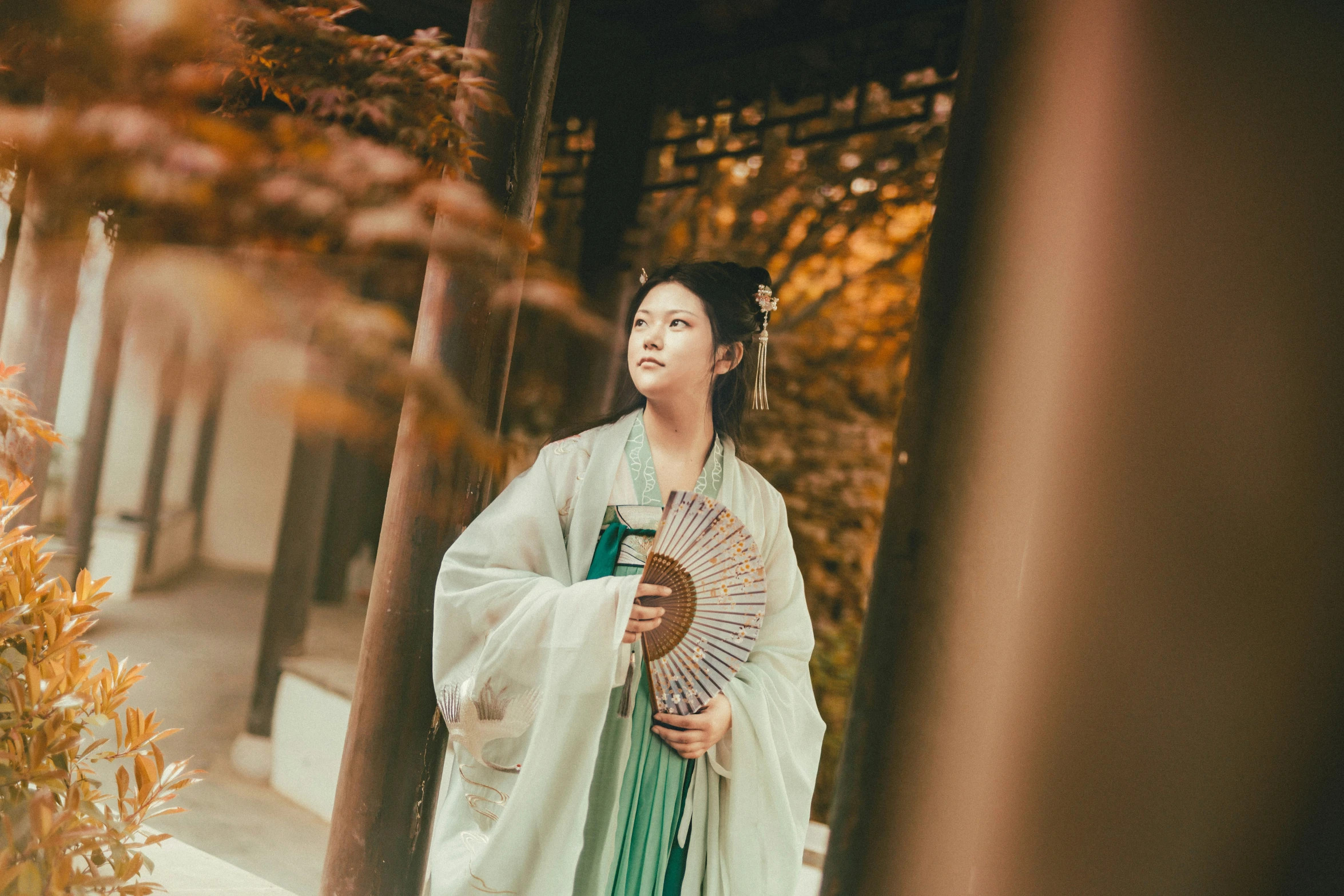 a woman wearing an oriental kimono holds an umbrella