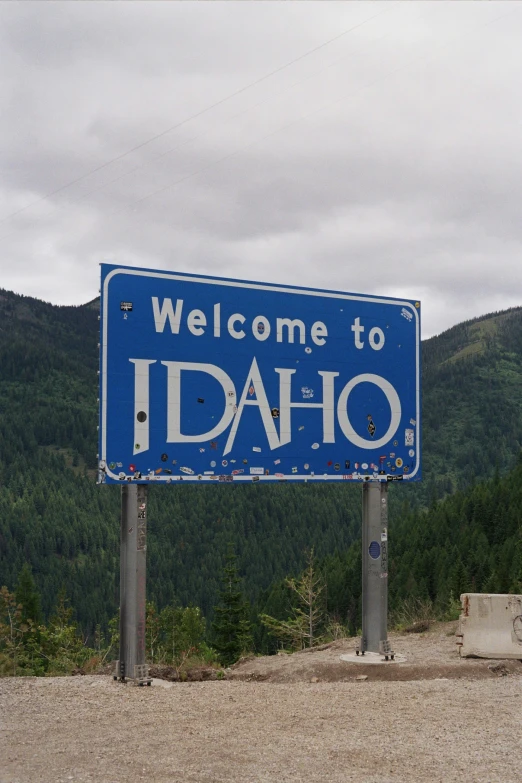 a welcome sign in front of some hills