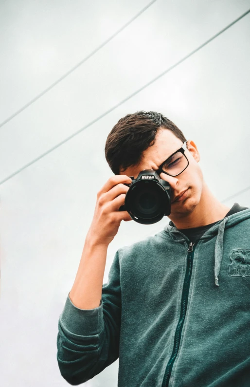 a man in a hoodie takes a po with a camera