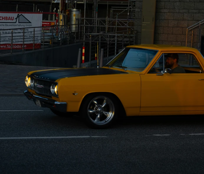 a man driving an old yellow car on the street