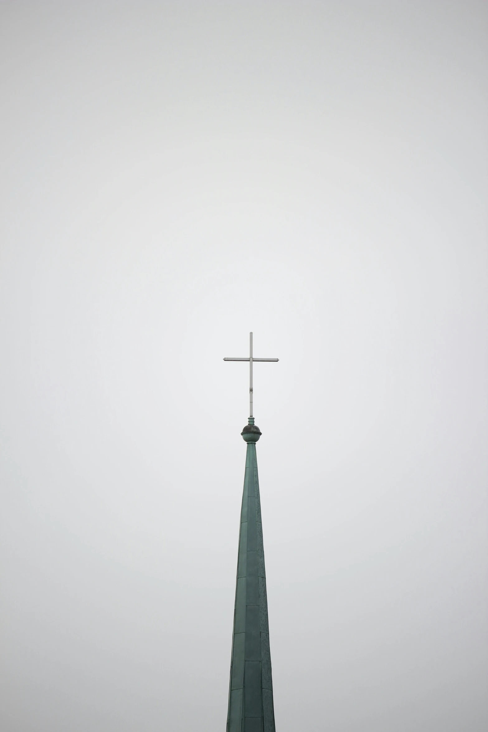 a cross sitting on the top of a steeple in the fog