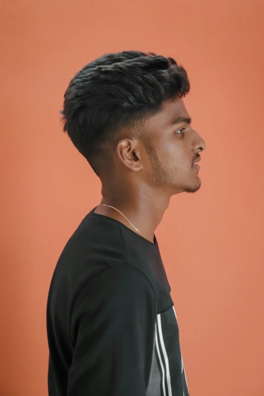 a guy is posing in front of an orange wall