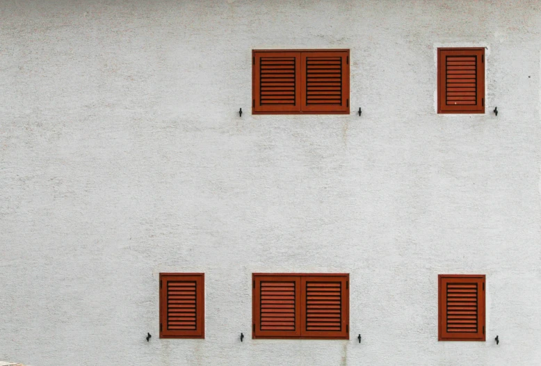 four brown windows on the side of a white building