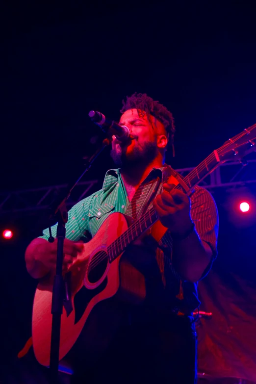 a man with dreadlocks on playing guitar