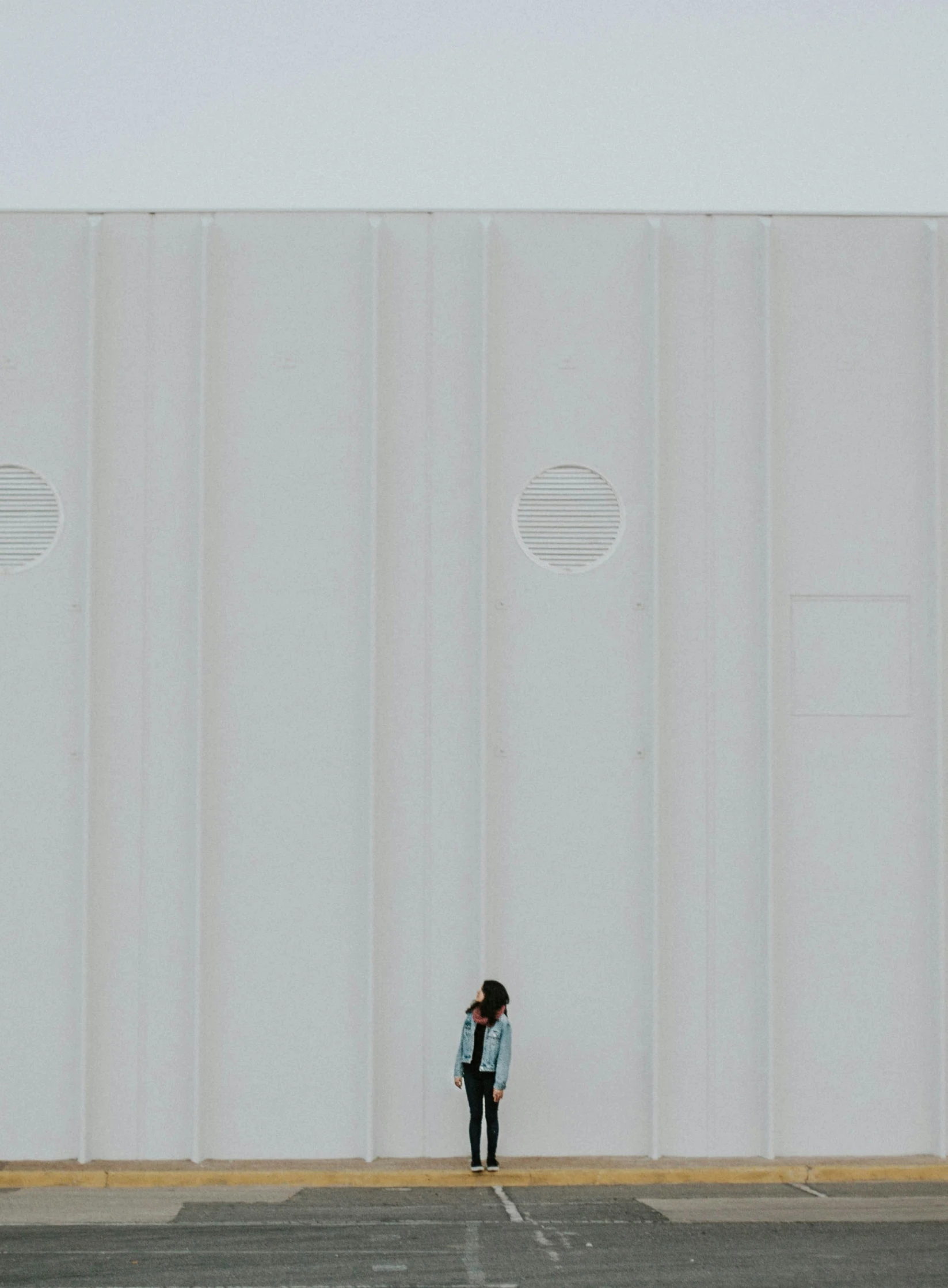 a person standing outside in front of white walls