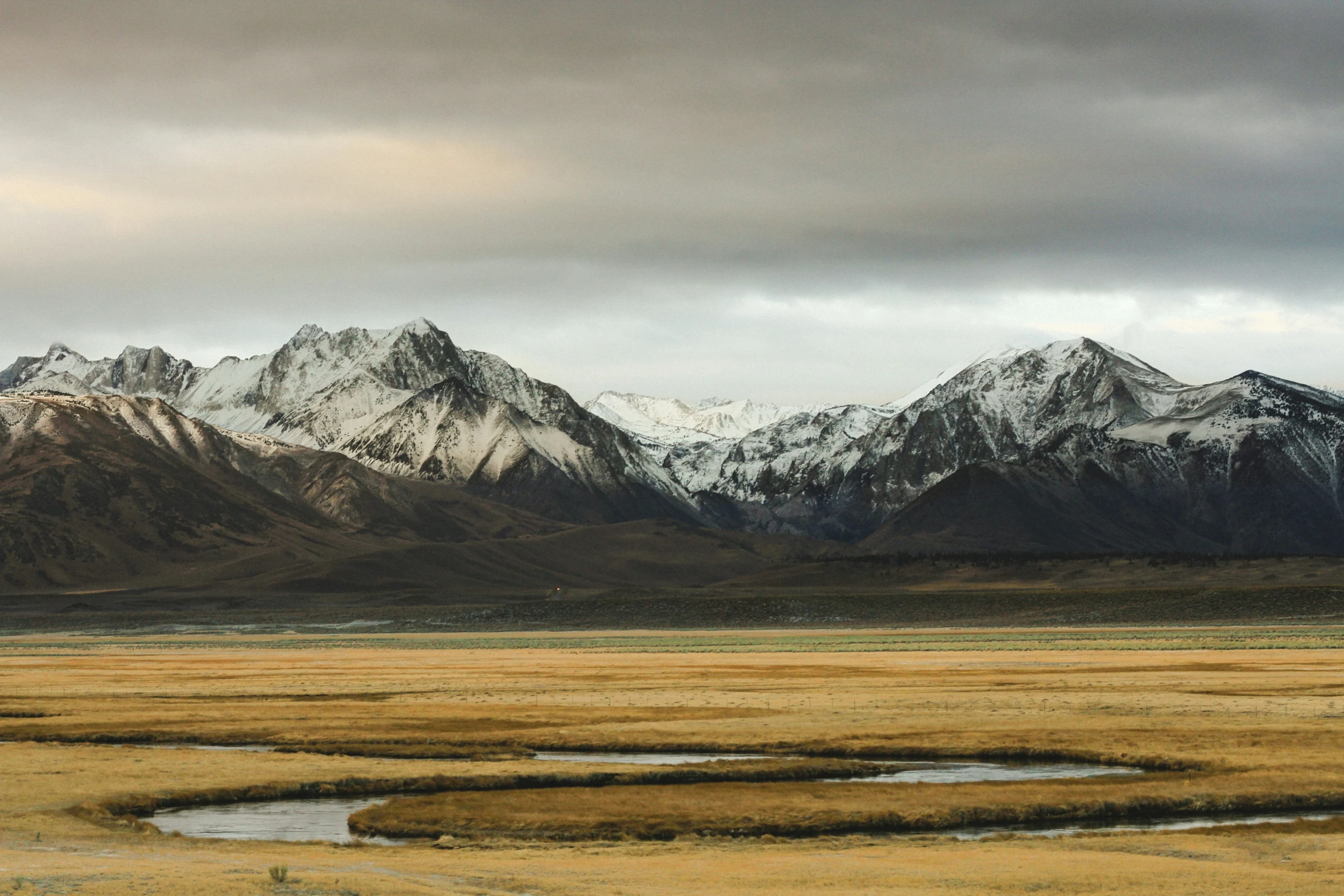 mountains and dry grass with a small pond in the middle