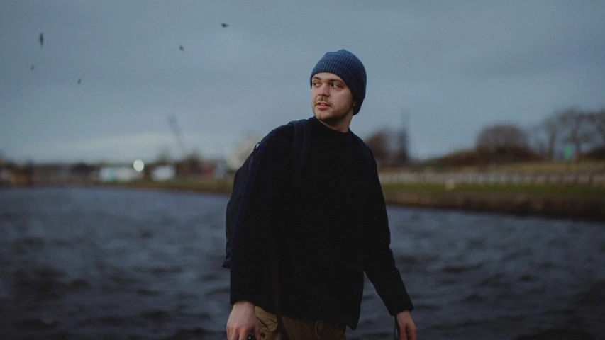 man holding his skateboard on his hip in the middle of an overcast day