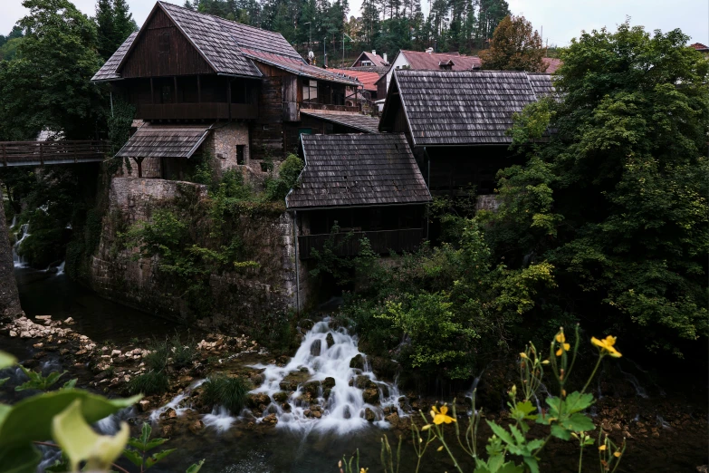 the house is perched above a stream and is next to a bridge