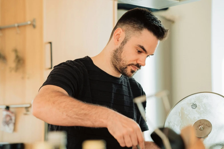 a man in black shirt cooking with pizza crust