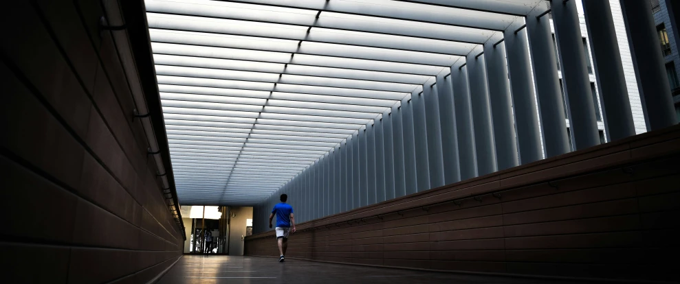 a walkway and a person walking down one side of it with windows