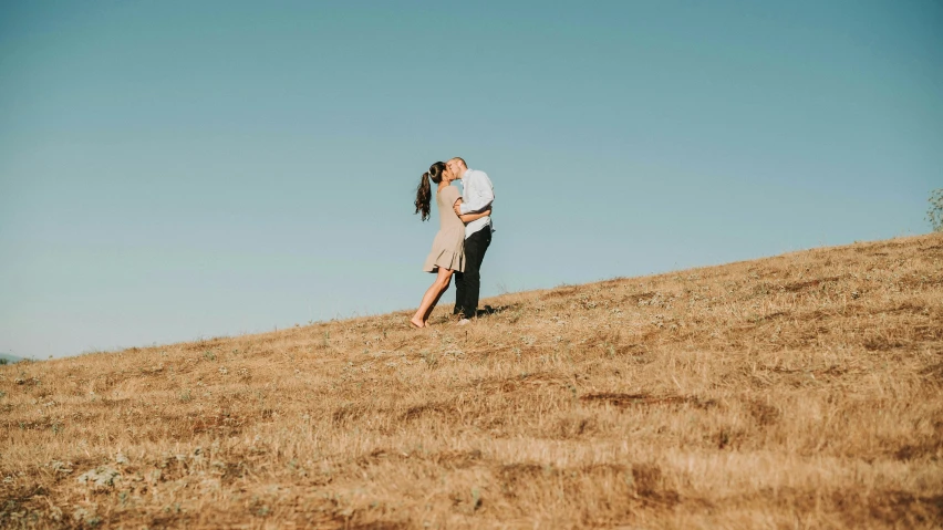 a man and woman on a hill kissing