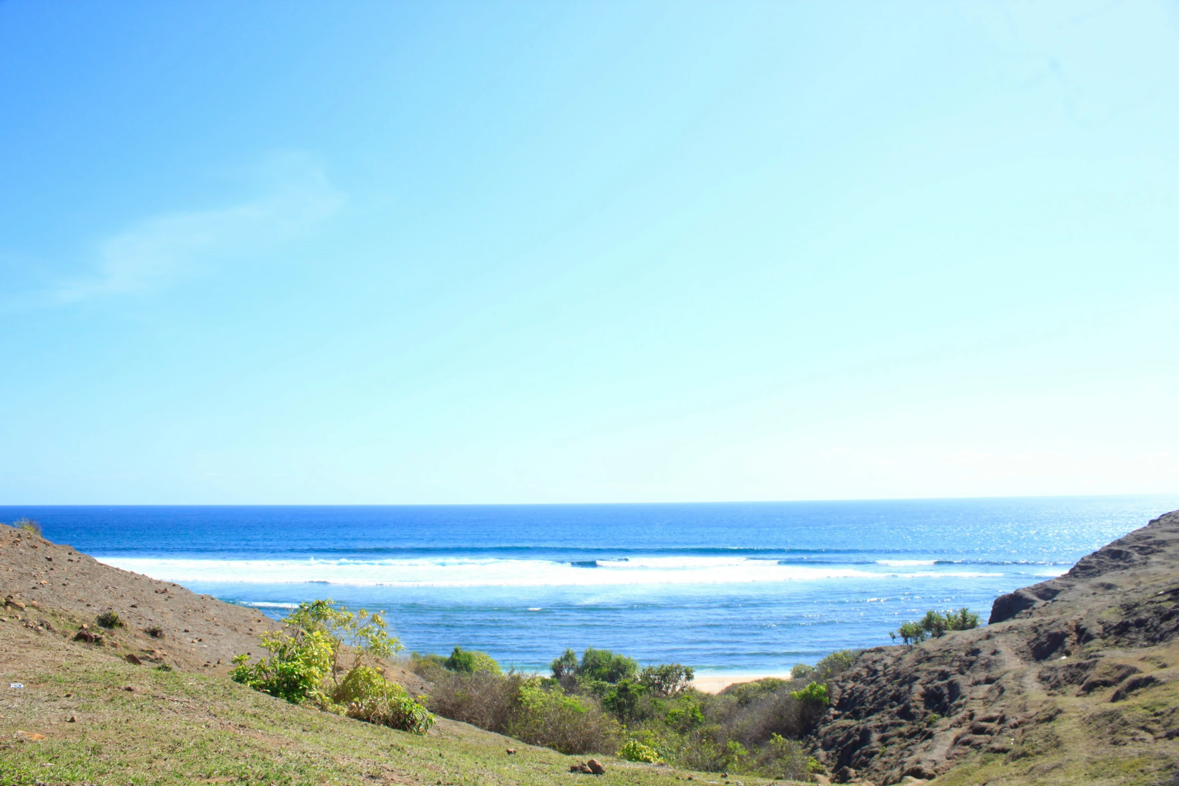 a large body of water surrounded by grassy hills