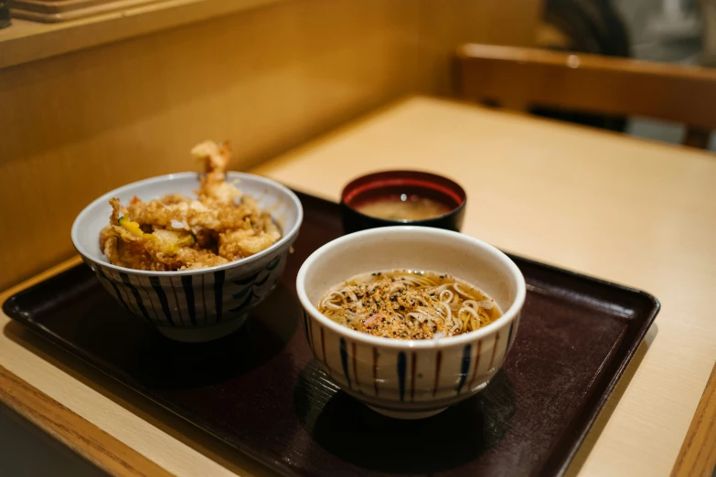 an asian meal is presented in bowls on a tray