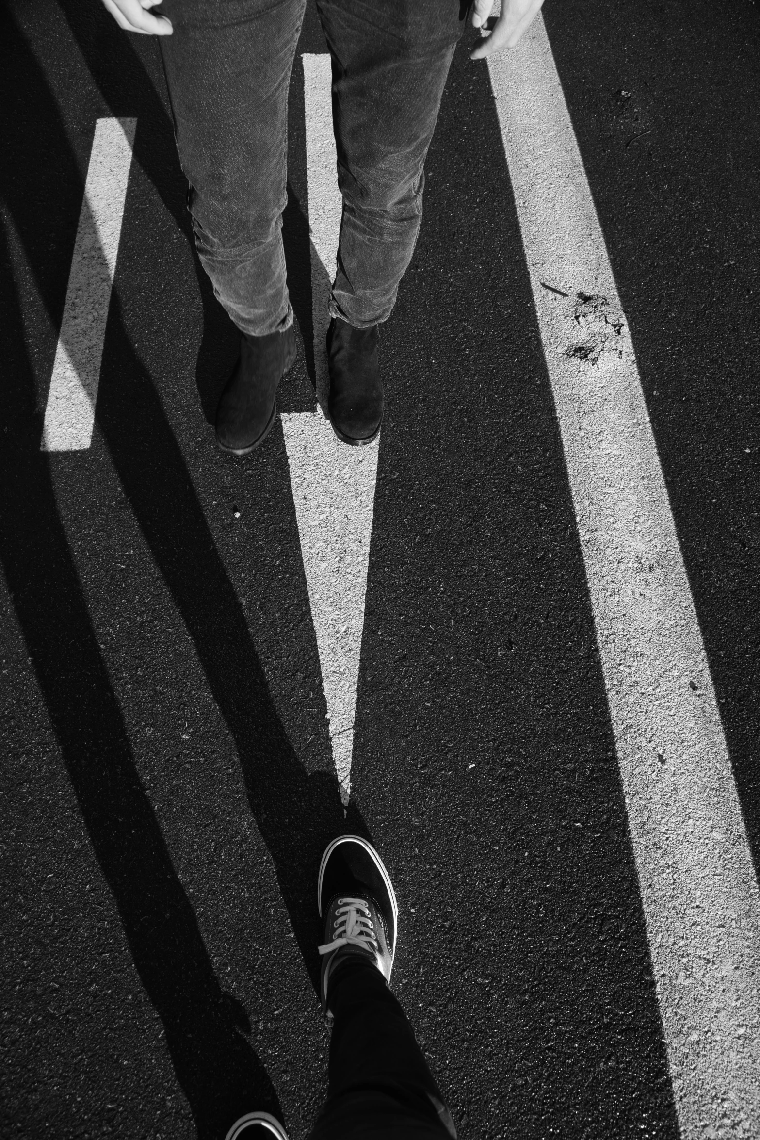 person in shoes standing at the edge of an arrow on the street