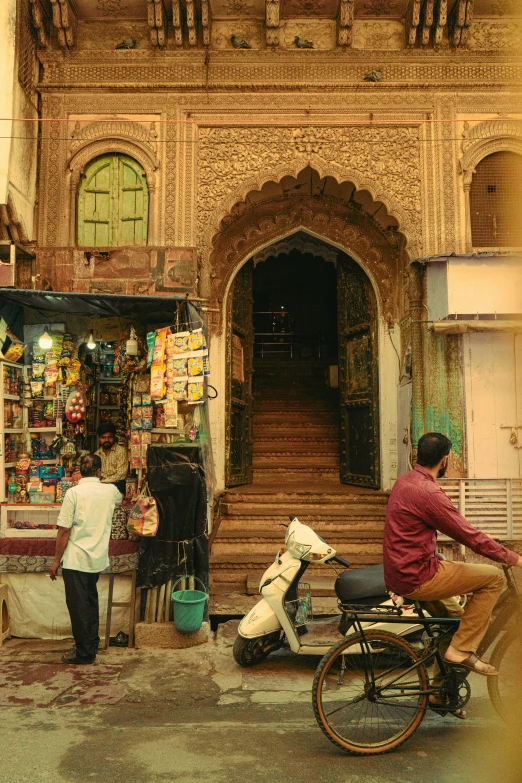 man and dog sitting on a bicycle near the entrance to an elaborate building