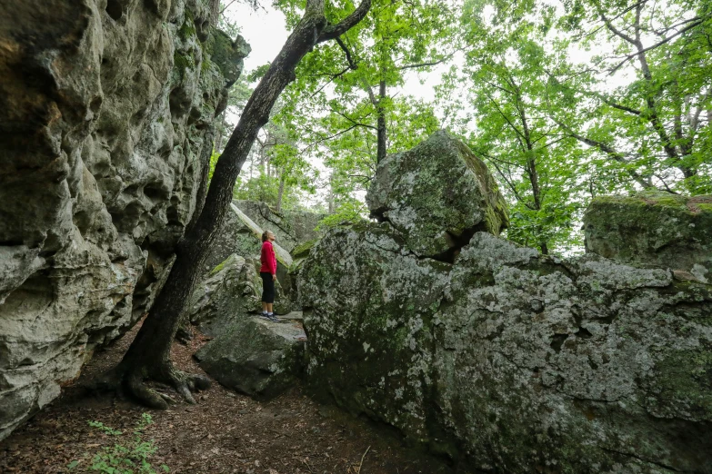 man walking on the pathway between two huge rock formations