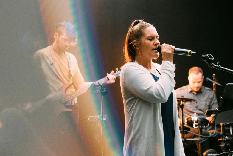 a woman is standing on a stage with her microphone up and singing