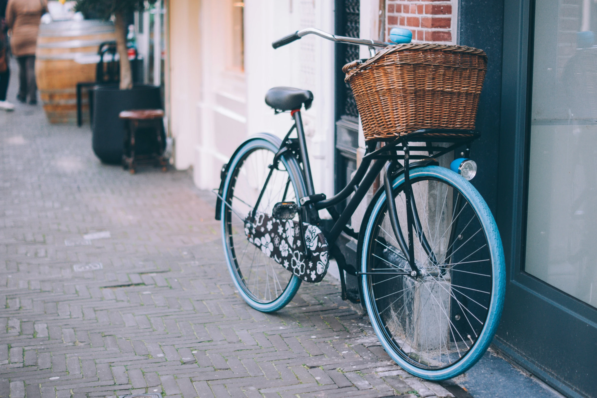 blue bicycle parked by a brick wall on a city street