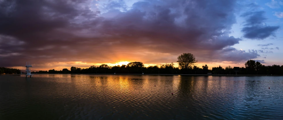 the sun is setting over the trees and the water