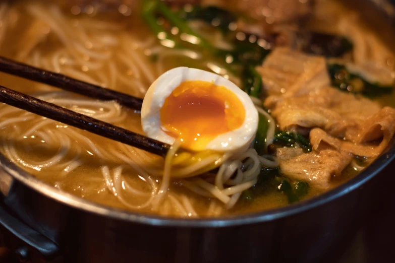 an egg sits on a piece of spaghetti in a pot