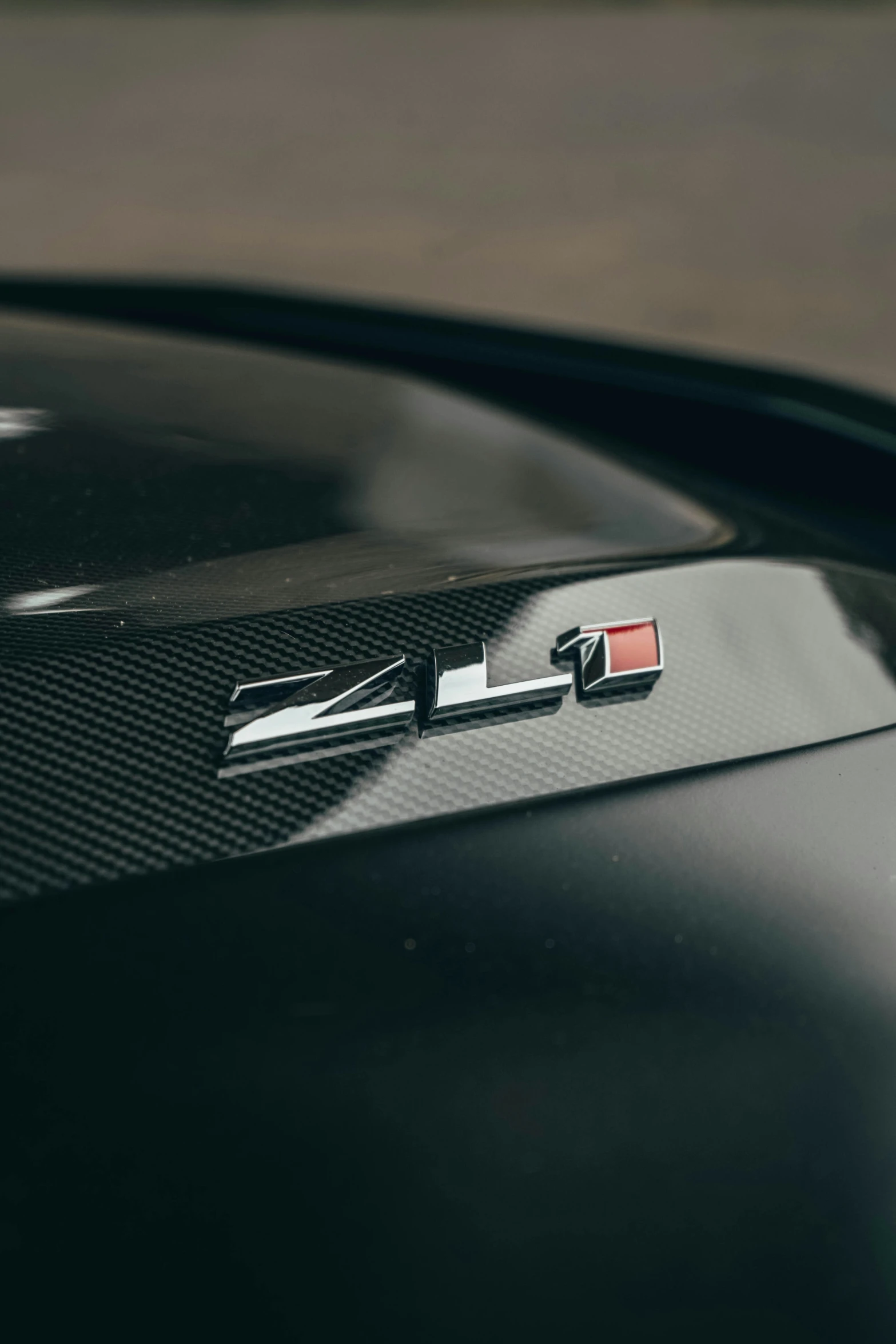 a black hood ornament with a chrome stripe